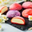 Multi-colored Japanese ice cream Mochi in rice dough and Jasmine flowers on a concrete blue background. Traditional Japanese dessert on a black slate.