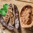 Carob pods and carob beans on the wooden table.